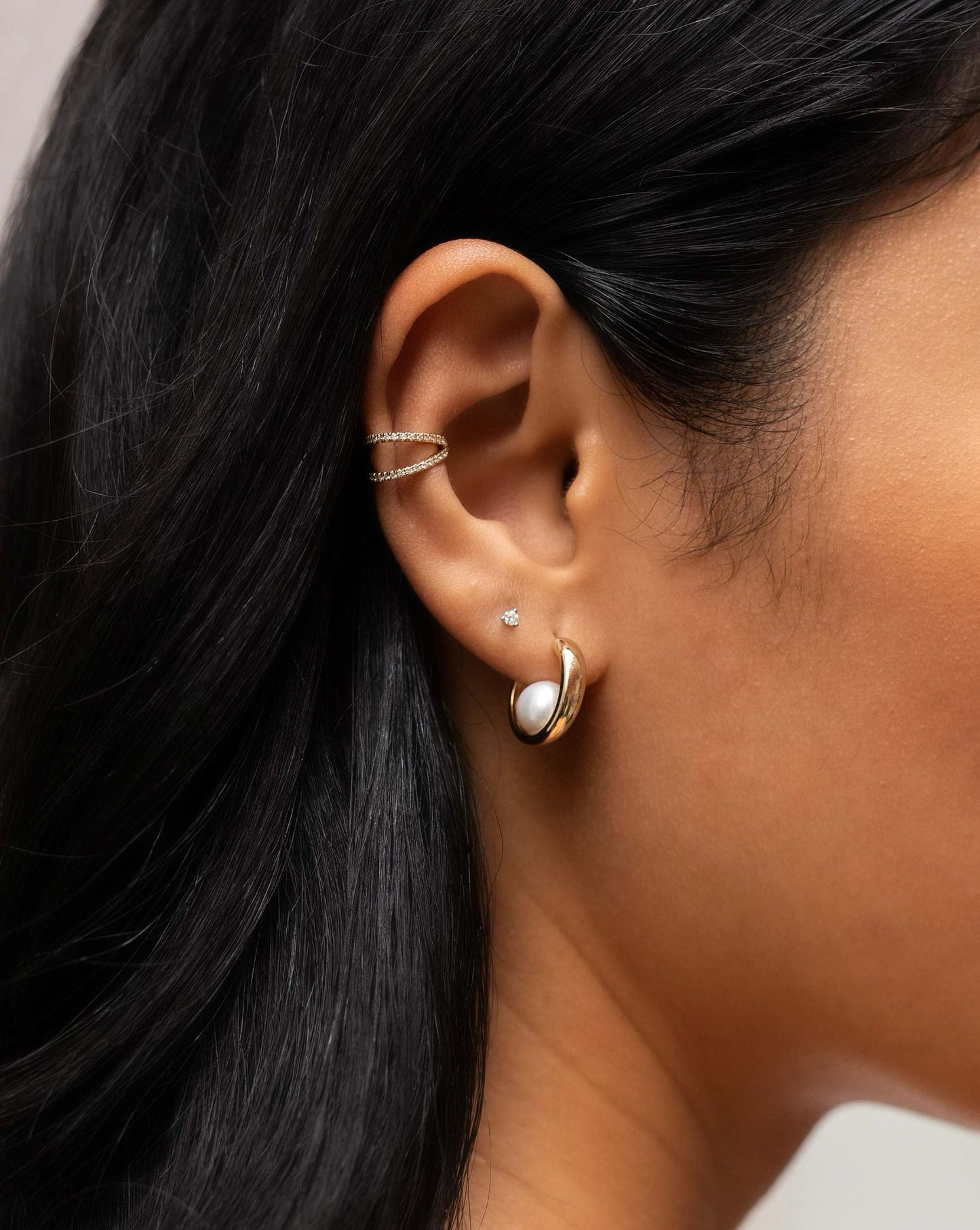 open double row diamond ear cuff, small round-cut diamond stud, and 14k yellow gold hoop with single pearl on inside of hoops on model
