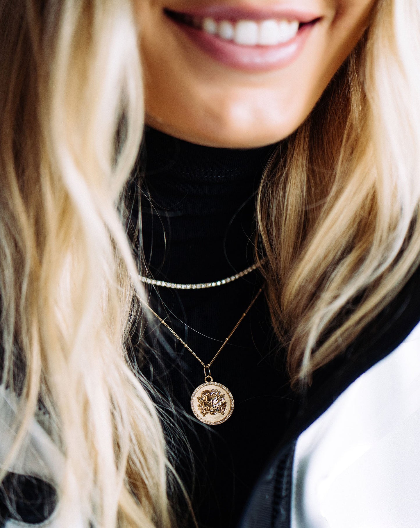 Zodiac Medallion Necklace on blonde model wearing black turtleneck and styled with a tennis necklace