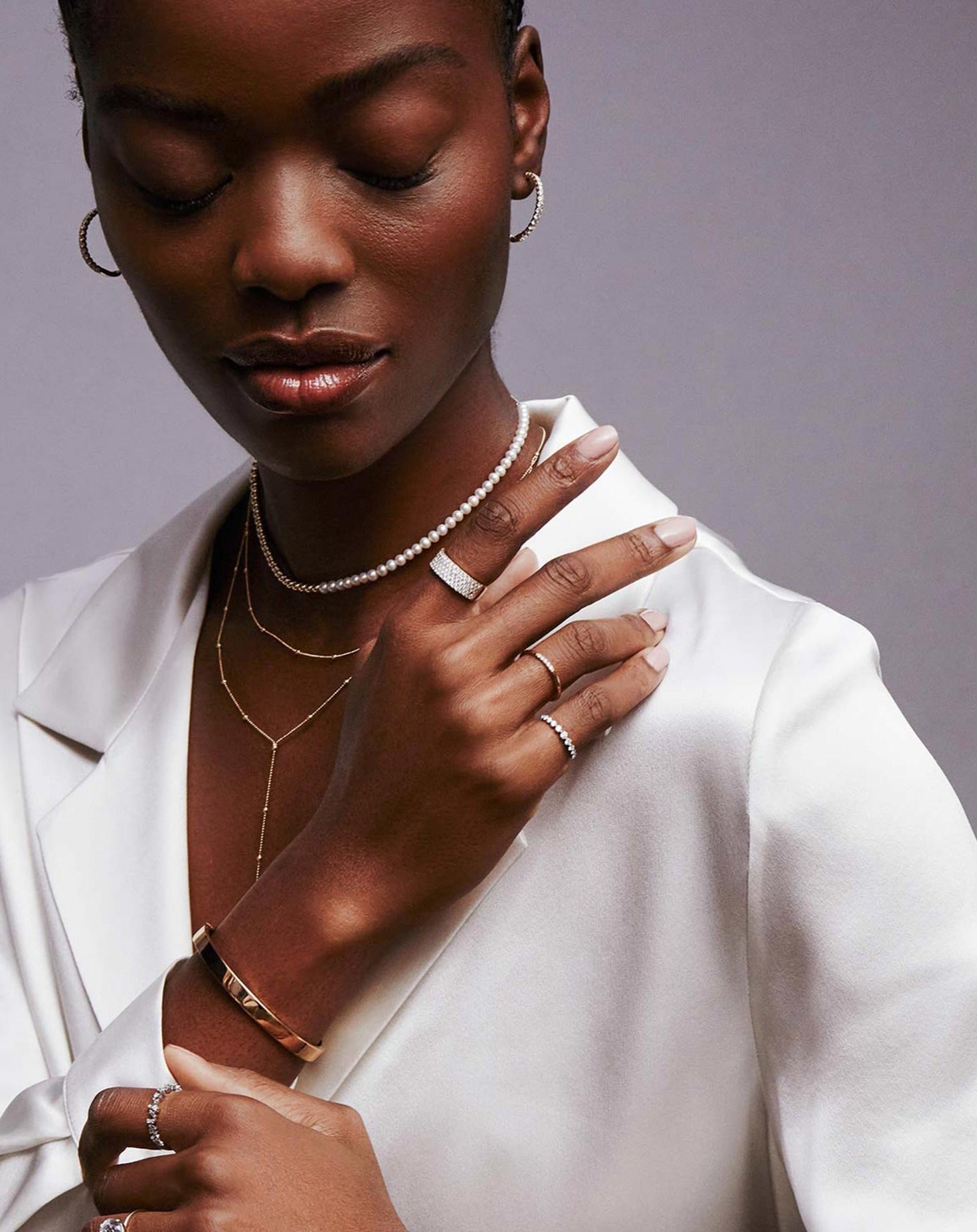 Ring Concierge Rings Five Row Stackable Pavé Ring on model, on wrist gold stackable bangle, diamond earrings and Multiway Pearl and Gold Beaded Necklace + Double Wrap Bracelet and Saturn Double Layer Lariat Necklace