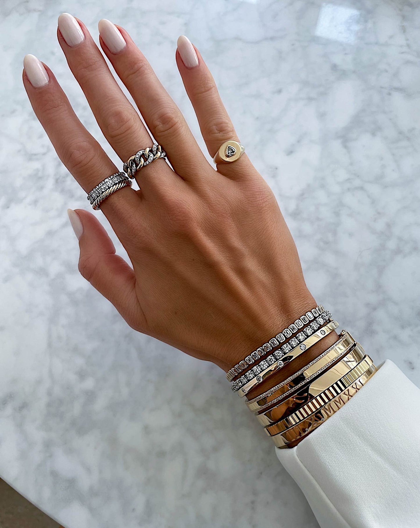 Ring Concierge twisted cable ring - on-model wearing the ring on her pointer finger and styled with gold rings and bracelet stack of mixed metals